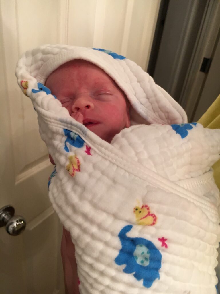 Newborn wrapped up in a muslin hooded robe blanket after bath
