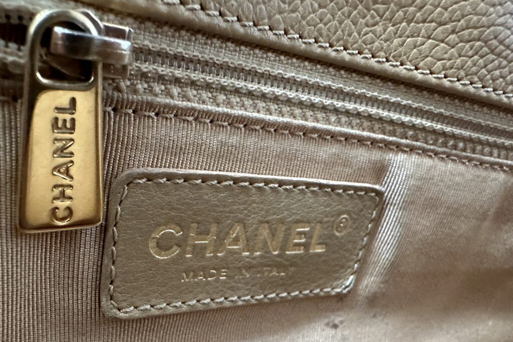 Close up photo of Vintage Chanel Executive Cerf Tote Bag Zipper Hardware Gold-Toned CHANEL Logo Zipper Pull