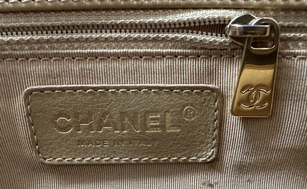 Close up photo of the double CC Chanel Logo Zipper Pull Hardware in Gold-Tone inside the Vintage Executive Cerf Tote Bag - reverse of the zipper is the CHANEL logo