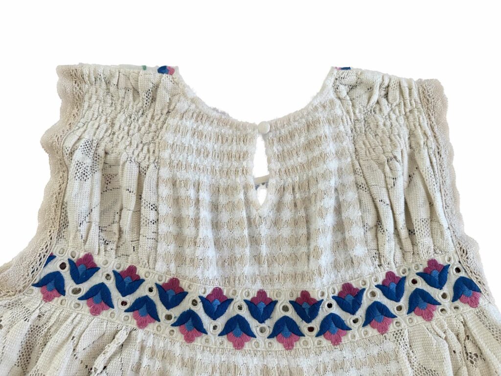 Back fabric covered button of the babydoll lace and embroidery tank top from Anthropologie