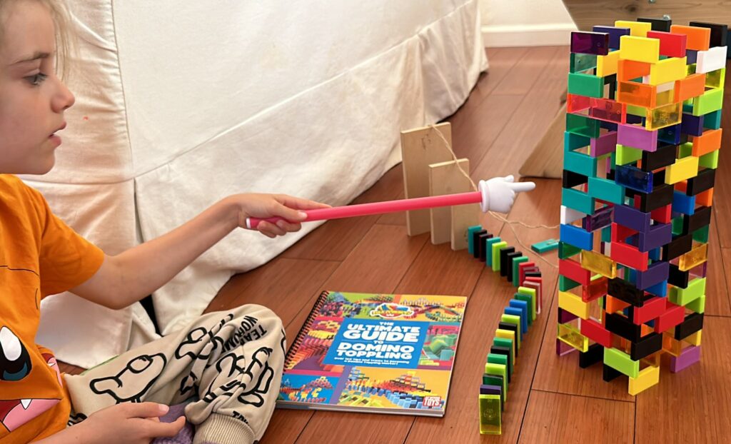 Using a plastic fake finger to topple dominoes it's topple time